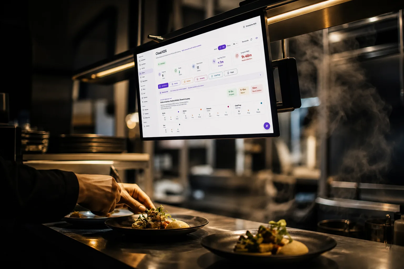 A kitchen pass mid-service, the Servio kitchen screen glowing above the plates
